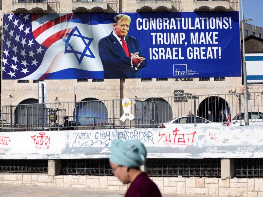 Una mujer camina en  en Jerusalén  cerca de un cartel de felicitación a Donald Trump después de ganar las elecciones presidenciales.