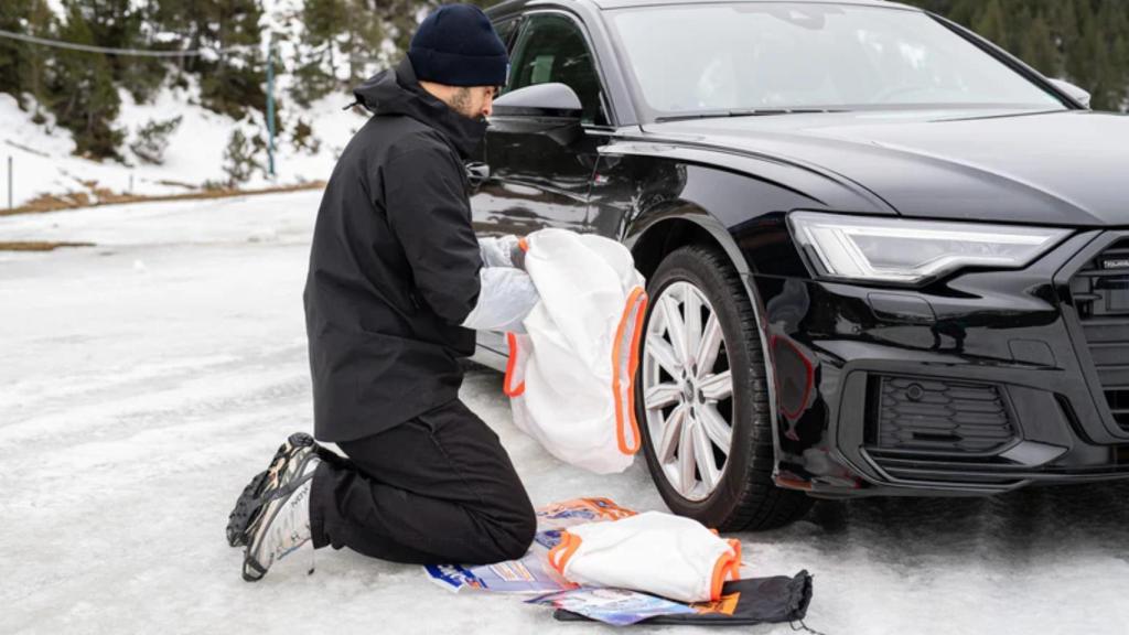 Una persona colocando una cadena de nieve textil Musher.