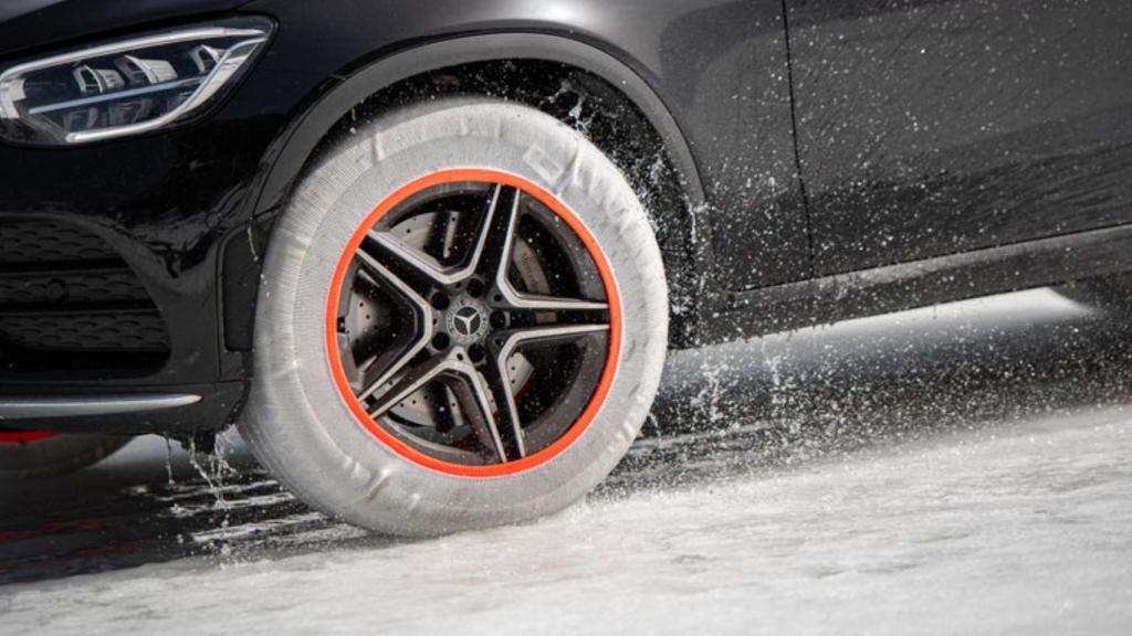 Un coche con una cadena de nieve textil Musher.