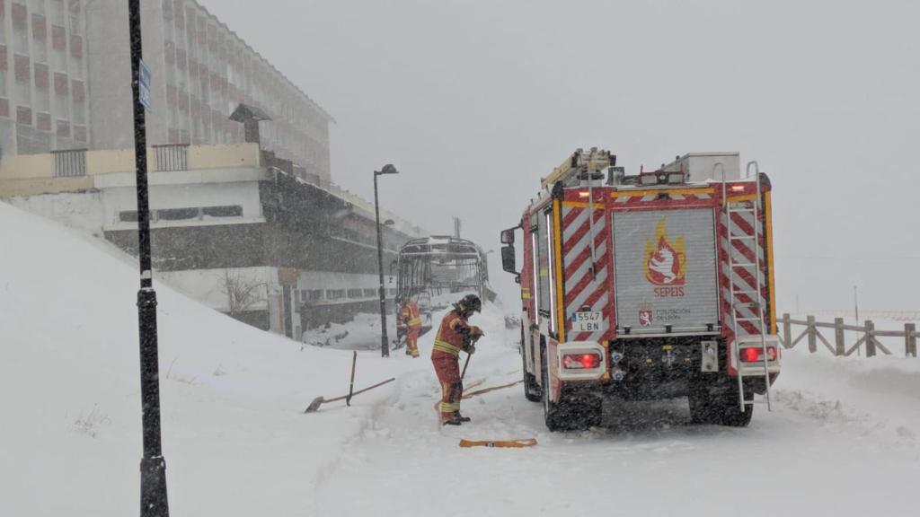 Los bomberos trabajan en la zona donde se ha incendiado el autobús en la estación de esquí de San Isidro
