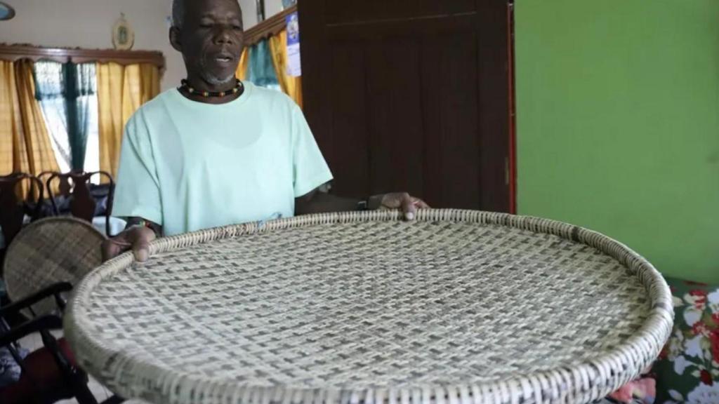 Fotografía de Ramón Álvarez sosteniendo un utensilio usado para la preparación del casabe, en Trujillo (Honduras).