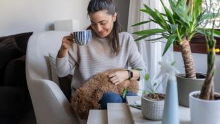 Mujer tomando café con un perro en su regazo.