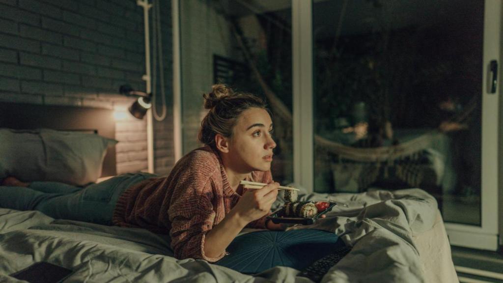 Mujer cenando sushi en la cama.