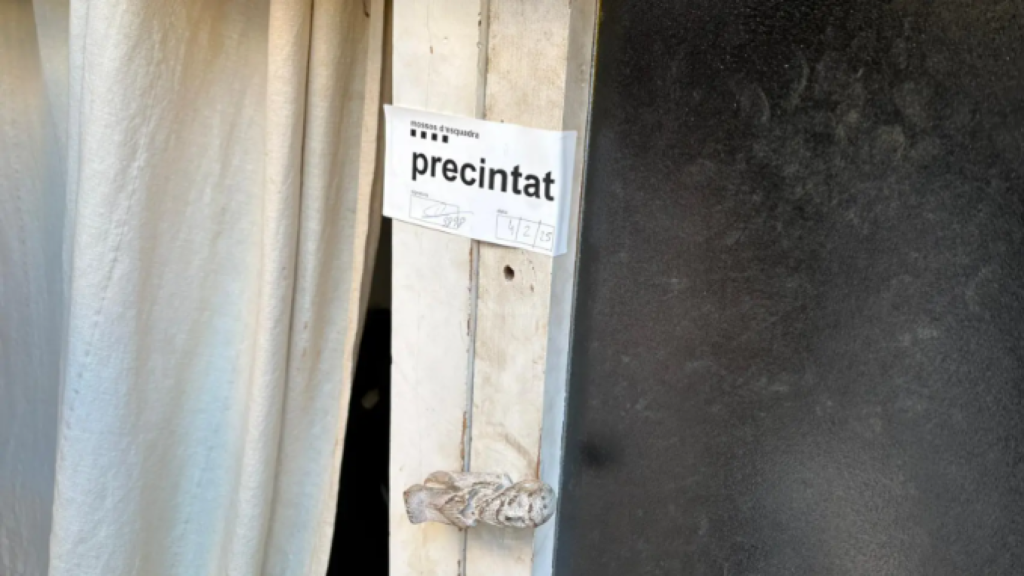 Precinto de los Mossos d' Esquadra sobre la cerradura del local donde ha aparecido el cadáver de Juan Carlos.