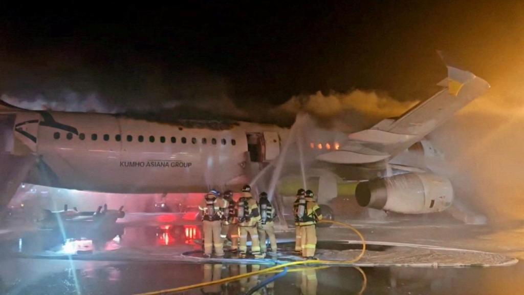 Unos bomberos apagando el fuego del avión de Air Busan.