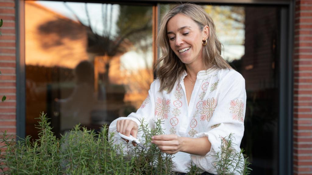 Paula corta romero de una de las macetas de su jardín.