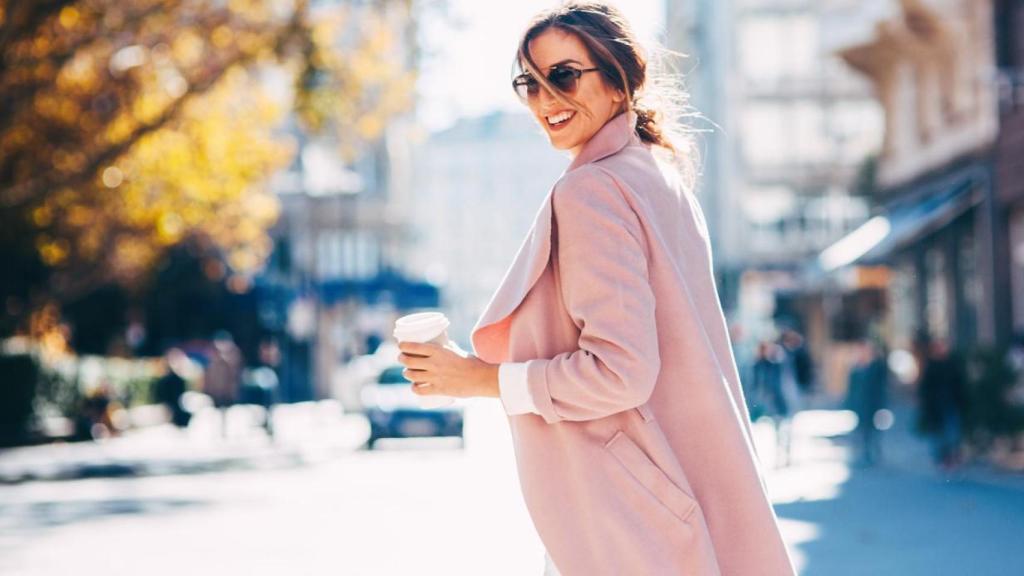 Mujer desenfadada caminando por la calle con un café.