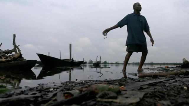 Un hombre arroja peces muertos a un río contaminado en Ogoniland, estado de Rivers, Nigeria, el 18 de septiembre de 2020.