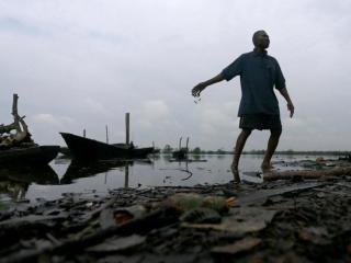 : Un hombre arroja peces muertos a un río contaminado en Ogoniland, estado de Rivers, Nigeria, el 18 de septiembre de 2020.