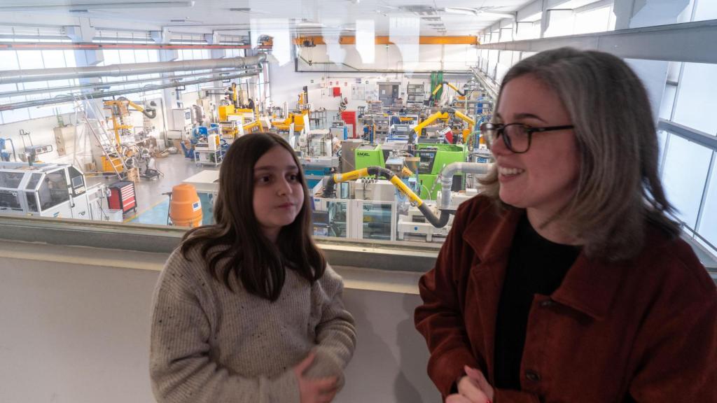 Aída y Neus, con la planta piloto de extrusión e inyección de AIMPLAS al fondo.