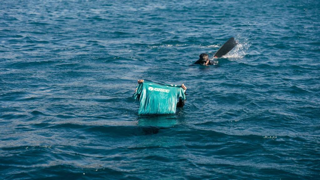 Imagen del momento en el que los buzos sacan la camiseta del fondo del mar.