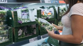 Imagen de archivo de una mujer comprando lechuga en un supermercado.