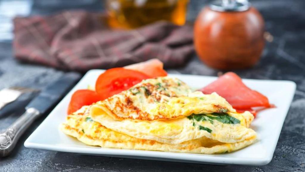 Tortilla francesa acompañada de tomates.