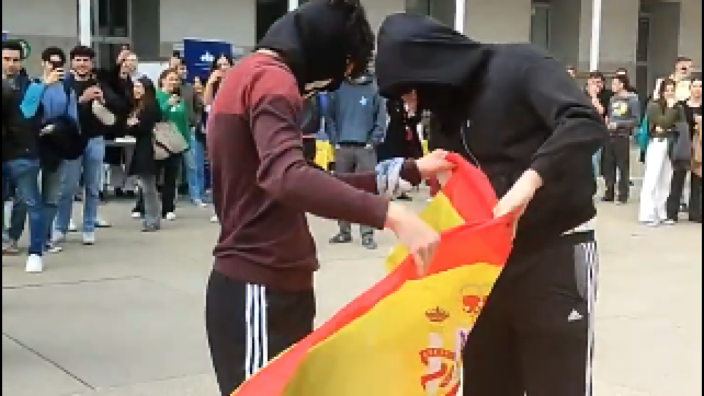 Los jóvenes tratando de quemar la bandera de España.