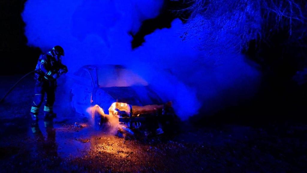 Un bombero sofocando las llamas del vehículo