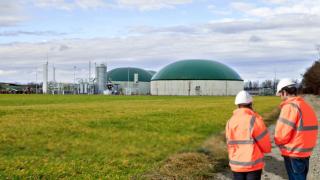 Imagen de dos operarios y, al fondo, una planta de biometano.