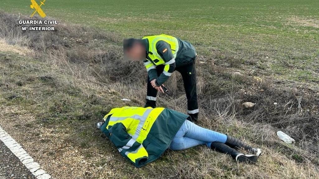 Un guardia civil atiende a la mujer hallada inconsciente en el arcén de una carretera de Palencia