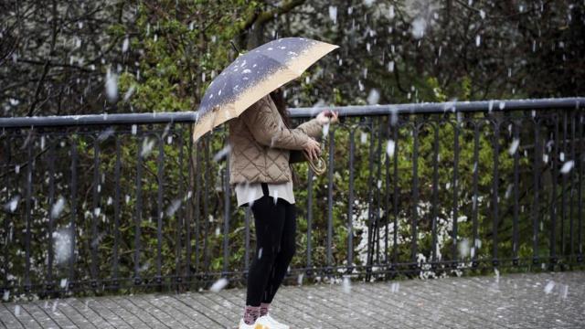 Una persona se resguarda del frío y el aguanieve.