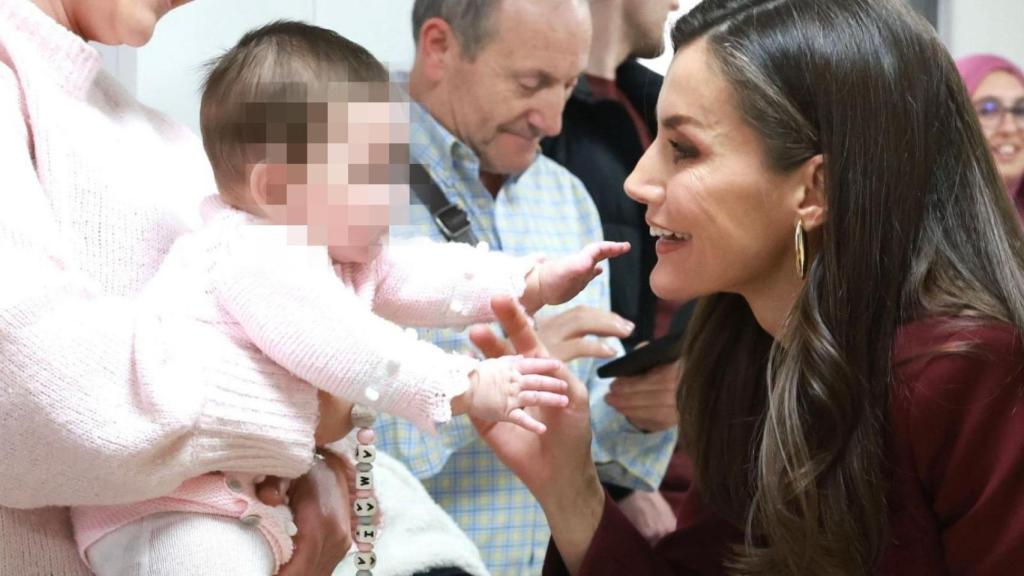 La Reina, en un momento de la visita con un bebé.
