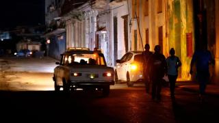 A group of people walk down a street without electricity service in Havana (Cuba).