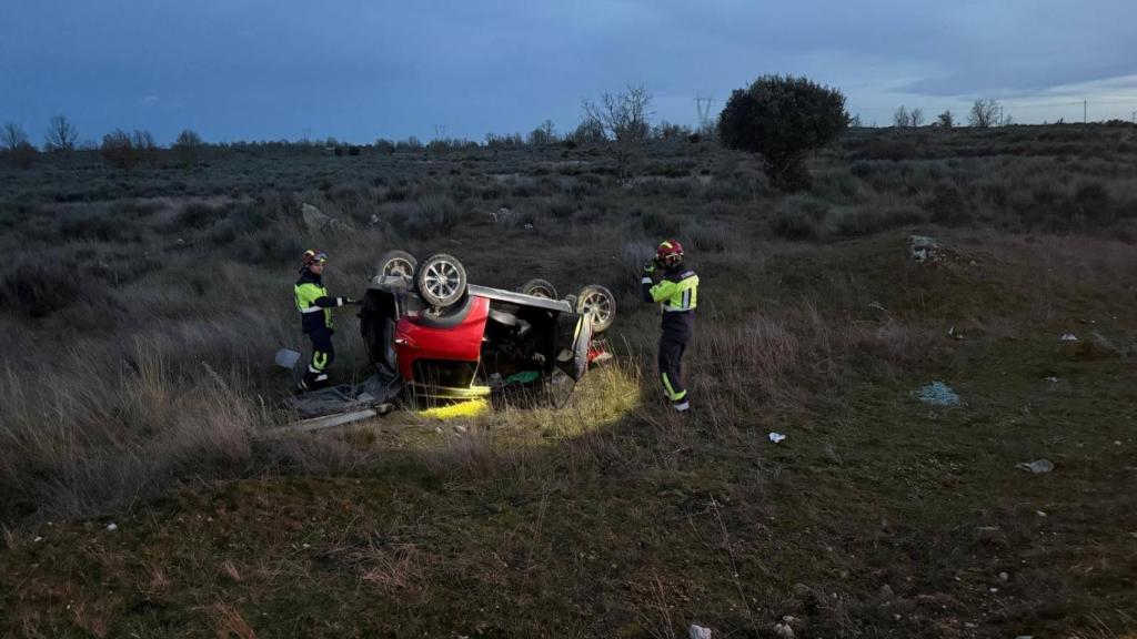 Imagen del vuelco del coche en una carretera de Zamora y dos guardias civiles trabajando en el lugar del accidente