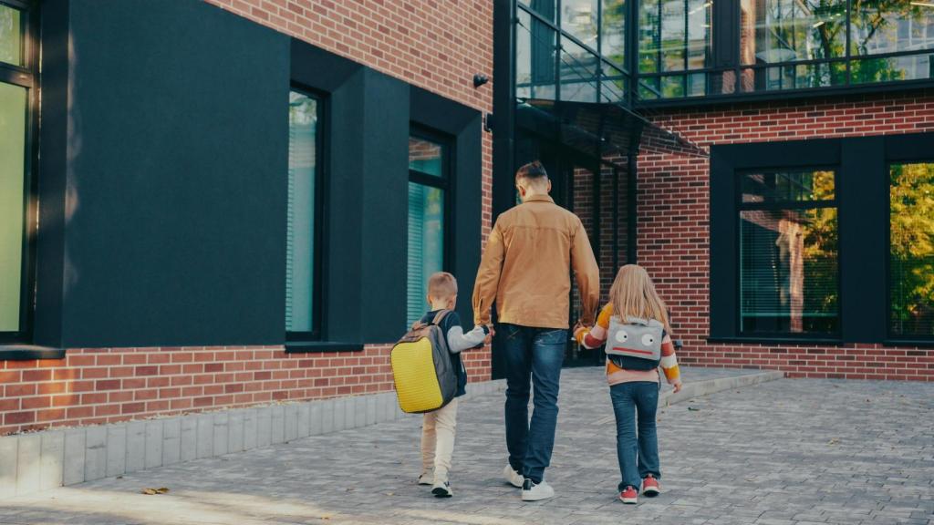 Un padre acompañando a sus hijos al colegio