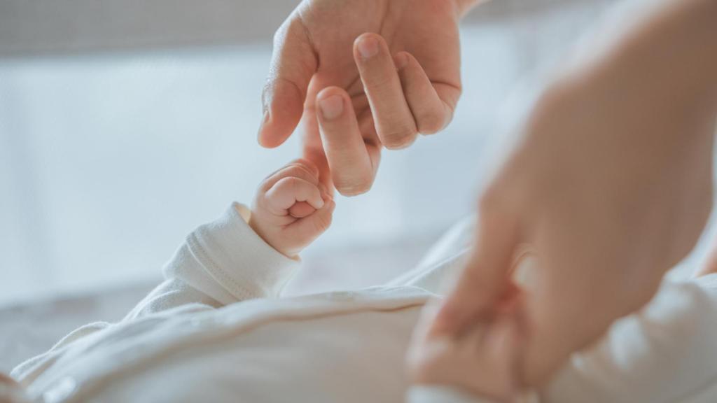 Un bebé dando la mano a su madre, en una imagen de Shutterstock.