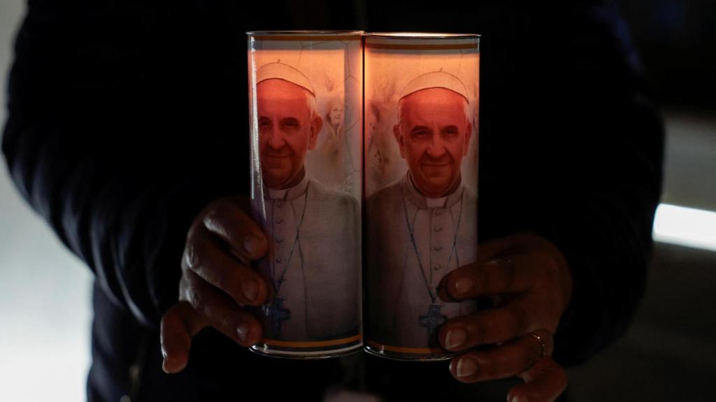 Un hombre sujeta velas con la imagen del papa a las puertas del hospital en el que estuvo ingresado en Roma.