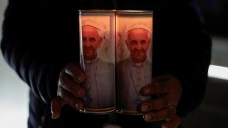 Un hombre sujeta velas con la imagen del papa a las puertas del hospital en el que estuvo ingresado en Roma.