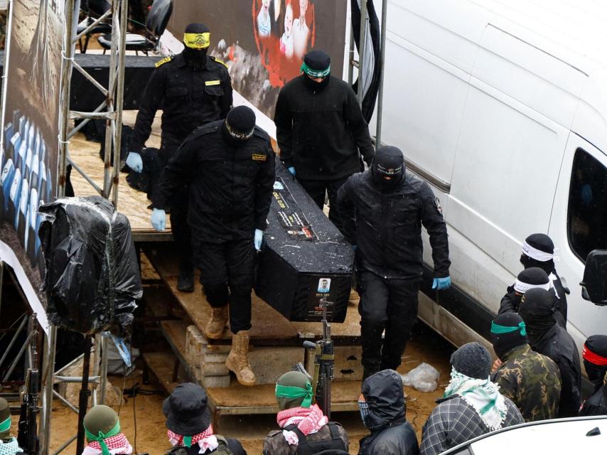 MIlicianos de Hamás con uno de los cadáveres entregados a Israel.