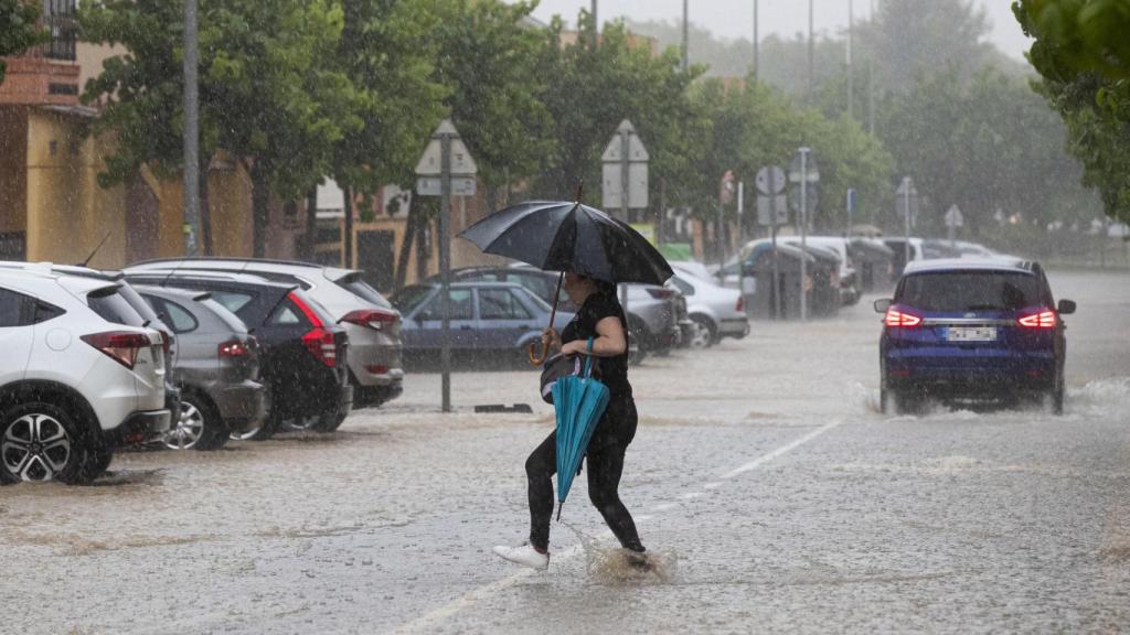 Una mujer intenta cruzar una calle en mitad de una lluvia torrencial en Madrid.