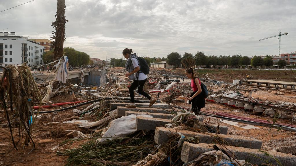 Dos chicas cruzan las vías de la Línea 1 del Metro de Valencia tras el paso de la dana, imagen de archivo. Efe / Manuel Bruque