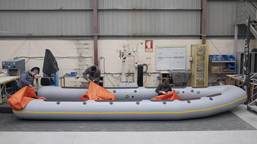 Tres empleados de Astec Boats elaboran una neumática en el interior de la fábrica.