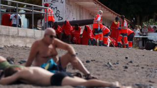 Varios migrantes, entre ellos algunos menores, atendidos en la playa de Las Galletas (Tenerife), tras la llegada del primer cayuco de 2025.