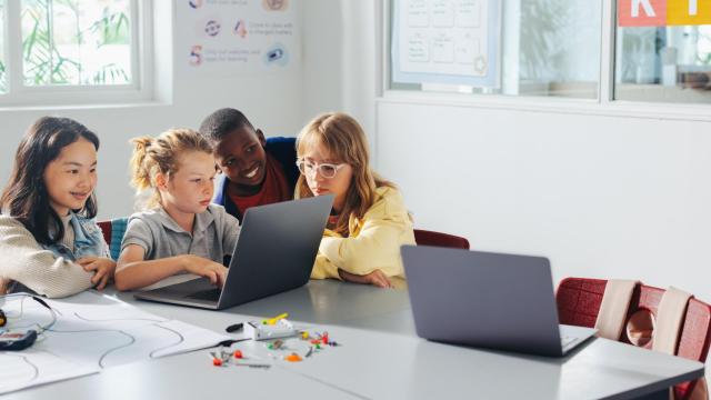 Grupo de niños en el aula trabajando con un ordenador portátil.