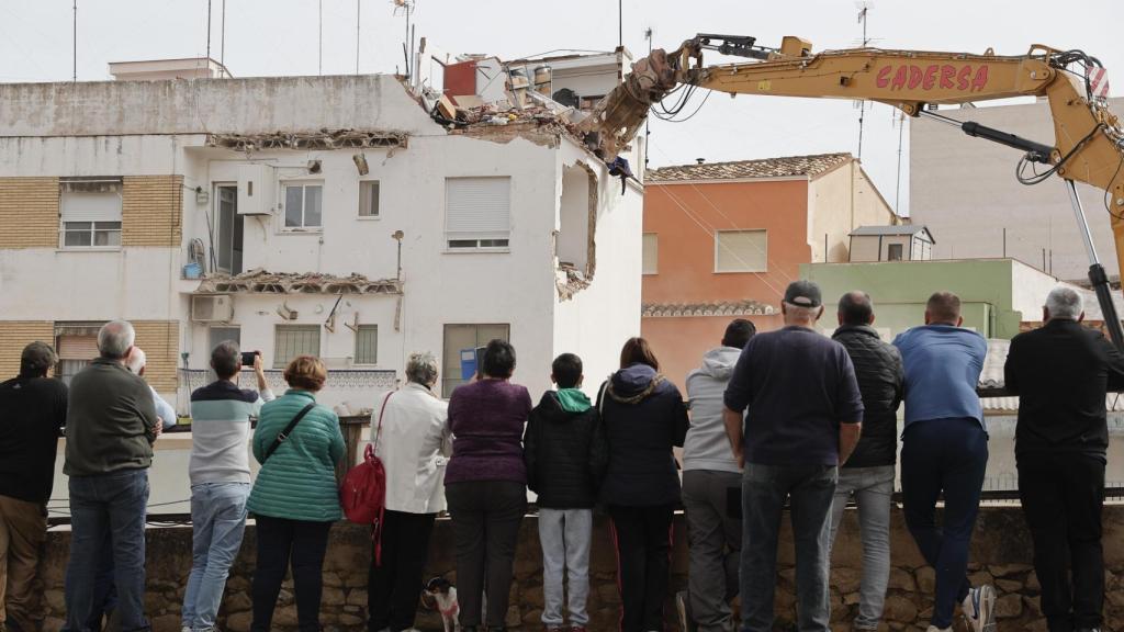 Varias personas observan el inicio de las obras de derribo de las casas afectadas por la dana en Chiva (Valencia). Efe /Manuel Bruque
