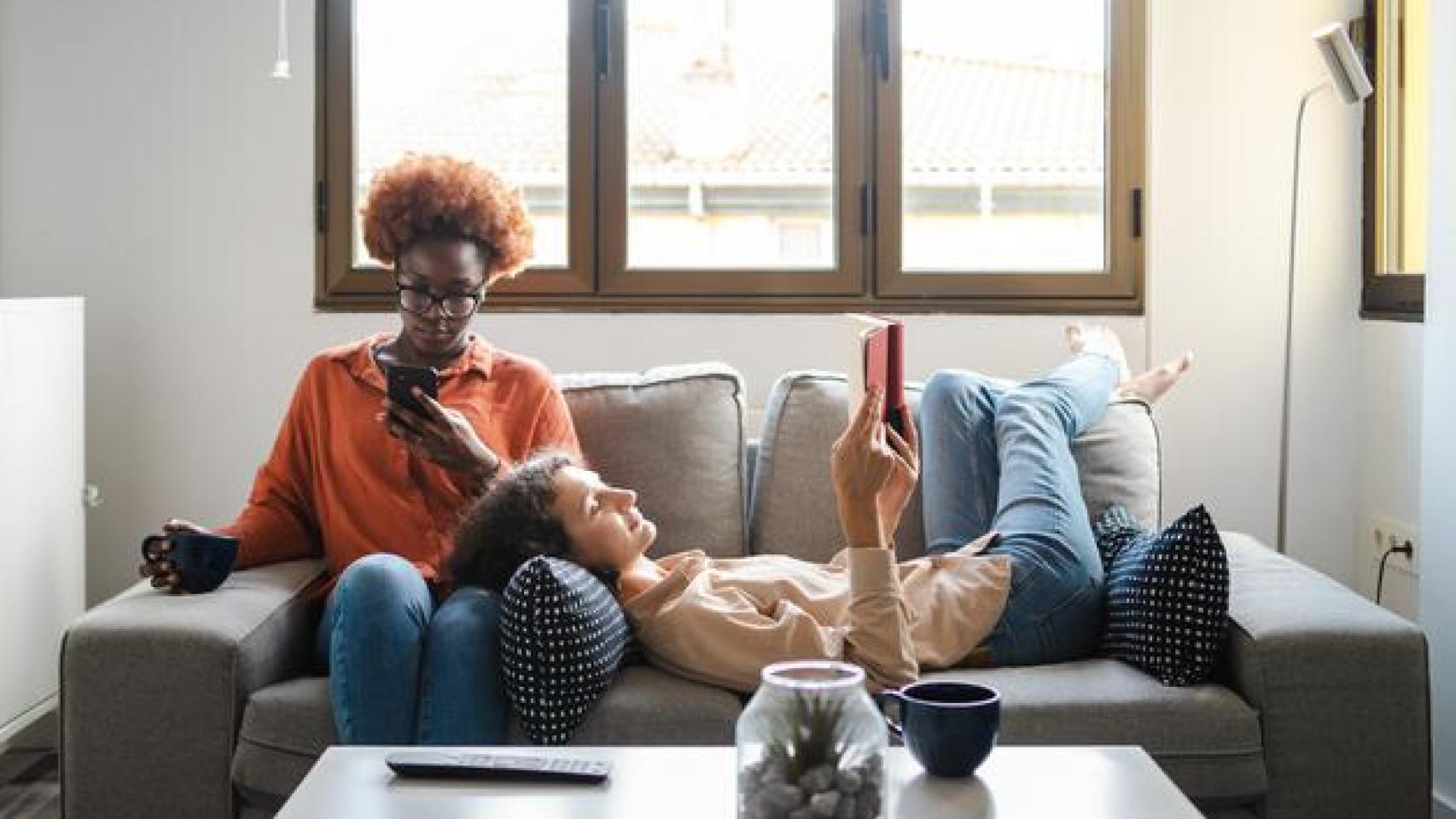 Dos mujeres en un sofá utilizando el móvil y la tablet.