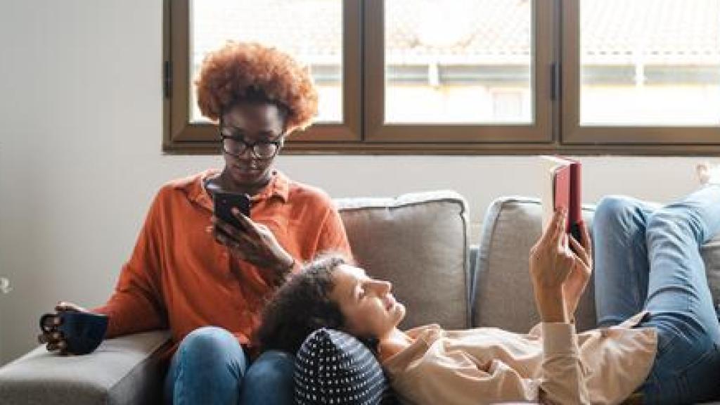 Dos mujeres en un sofá utilizando el móvil y la tablet.