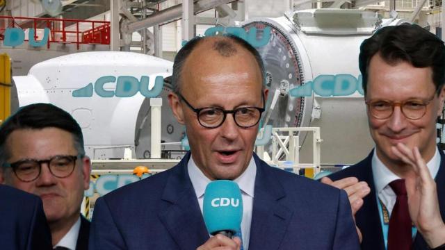 Fotomontaje del ganador de las elecciones en Alemania, el demócrata cristiano Friedrich Merz con su equipo y al fondo una industria de fabricación eólica.