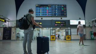 Un turista, frente a una de las pantallas de vuelos del aeropuerto de Sevilla.
