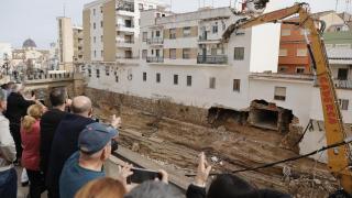Varias personas observan el inicio de las obras de derribo de las casas afectadas por la dana en Chiva (Valencia). Efe / Manuel Bruque