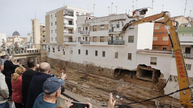 Varias personas observan el inicio de las obras de derribo de las casas afectadas por la dana en Chiva (Valencia). Efe / Manuel Bruque
