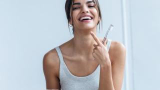 Mujer joven mostrando su sonrisa con el cepillo de dientes en la mano.
