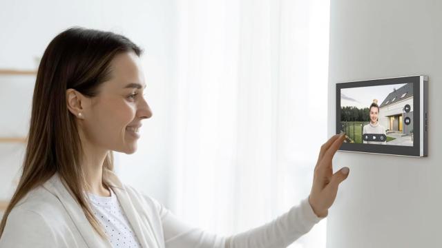 Una mujer usando una pantalla para ver quién llama a su puerta