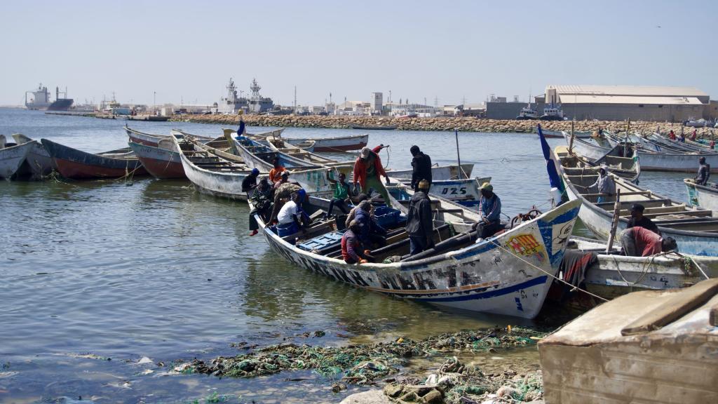 Un niño saluda desde el interior de un cayuco en las cercanías del puerto artesanal de Nuadibú, en el norte de Mauritania.
