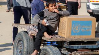 Un niño con un paquete de ayuda de la UNRWA en Jan Yunis.