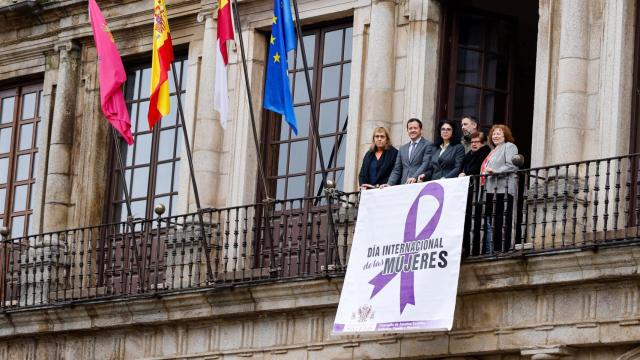 Colocación de la pancarta con el lazo morado por el 8M en el Ayuntamiento de Toledo.