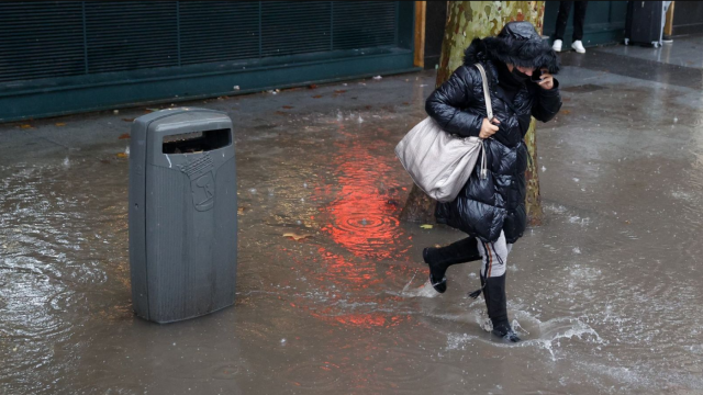 Una mujer se protege de la intensa lluvia en Madrid.