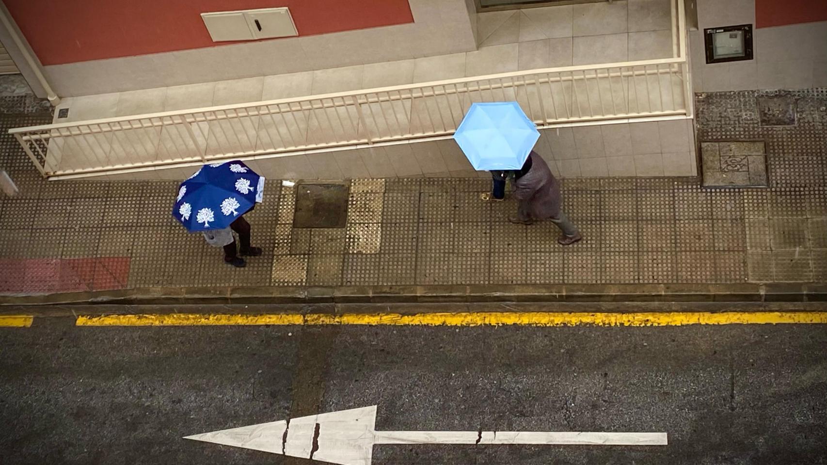 Varias personas protegiéndose de la lluvia en Málaga.