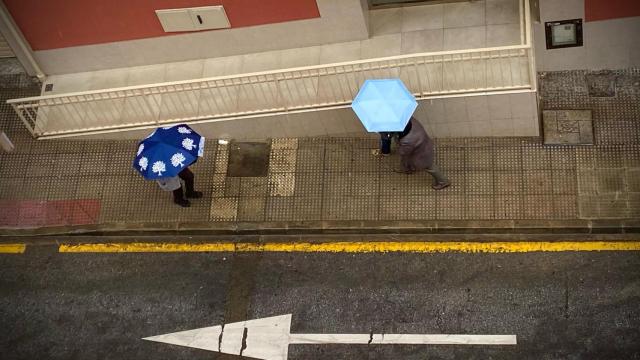 Varias personas protegiéndose de la lluvia en Málaga.